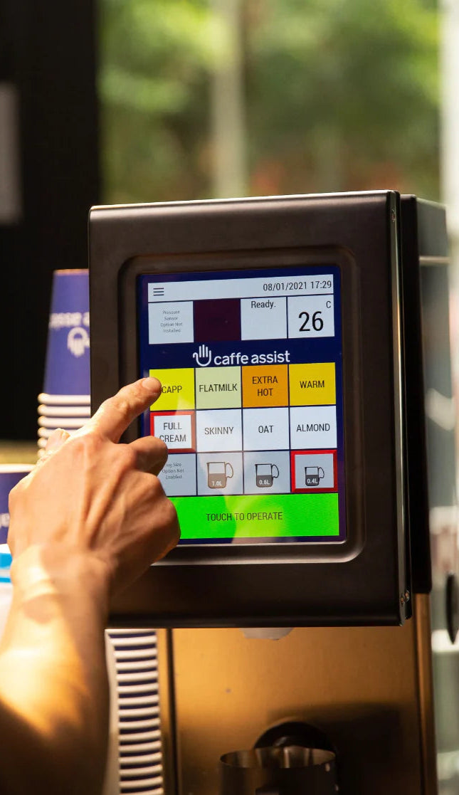 Person using a touchscreen machine with a coffee-related interface.